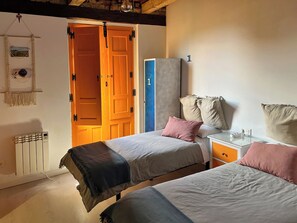 Une chambre avec deux lits, une armoire, un radiateur et une porte donnant sur une autre pièce.