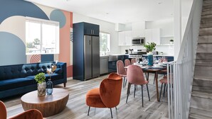 Een moderne woonkamer met een blauwe bank, oranje fauteuils en een houten salontafel.