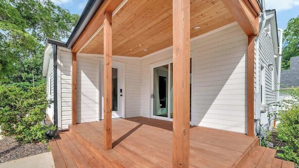 Une terrasse en bois avec un porche abrité, un revêtement extérieur blanc et un ciel dégagé.