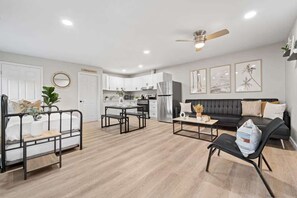 Un salon moderne avec un canapé, une table à manger et une cuisine en arrière-plan.