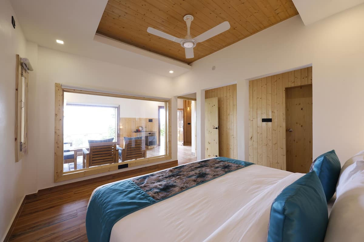 Een slaapkamer met een groot bed, houten plafond en uitzicht op een terras.