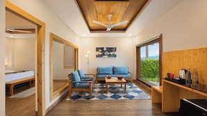A modern interior with a wooden ceiling, a sofa set, a dining table, and a view of greenery through a large window. - WelcomHeritage Arka Resort & Spa Rishikesh (Rishikesh)