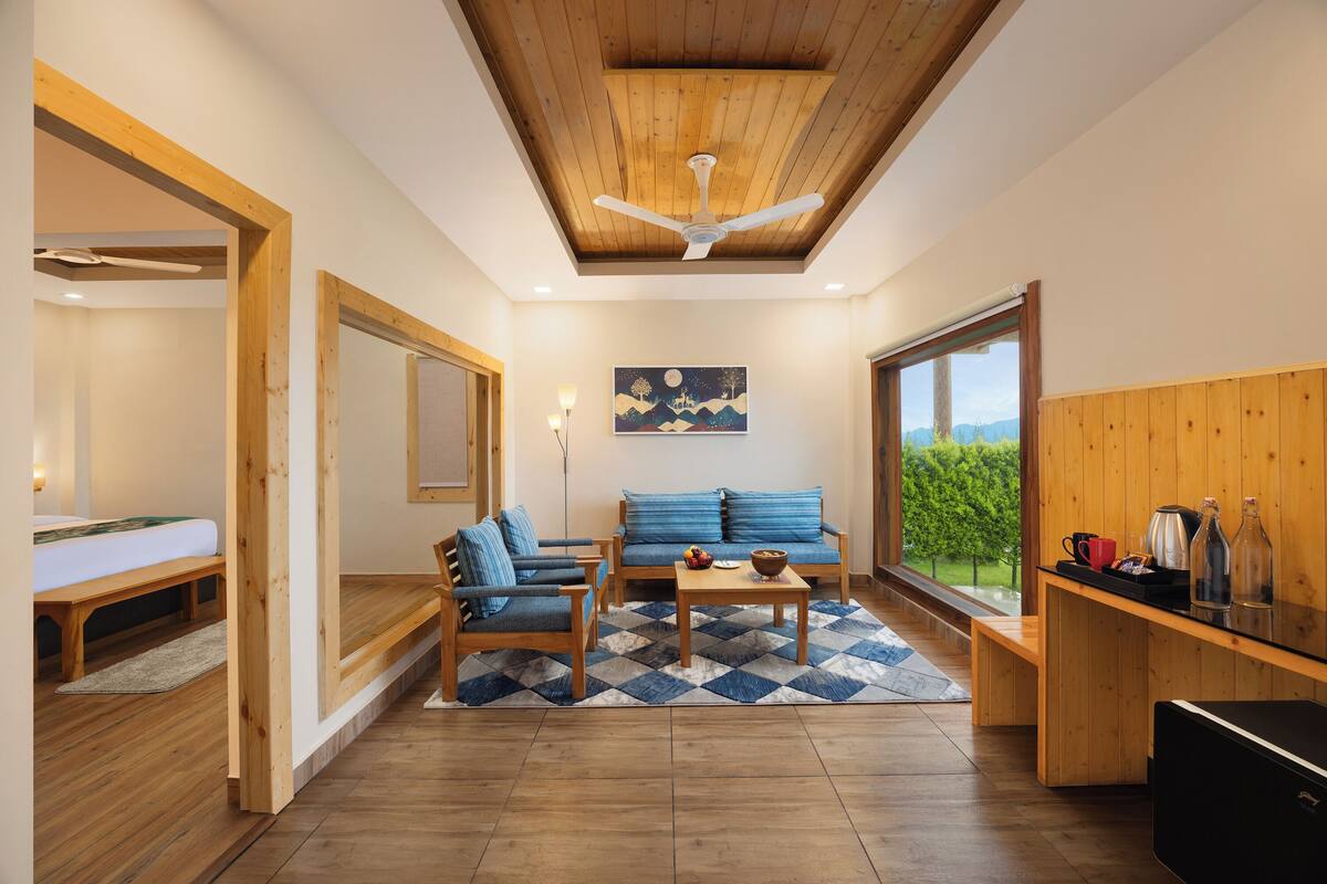 Een modern interieur met een houten plafond, een zithoek, een eettafel en uitzicht op groen door een groot raam.