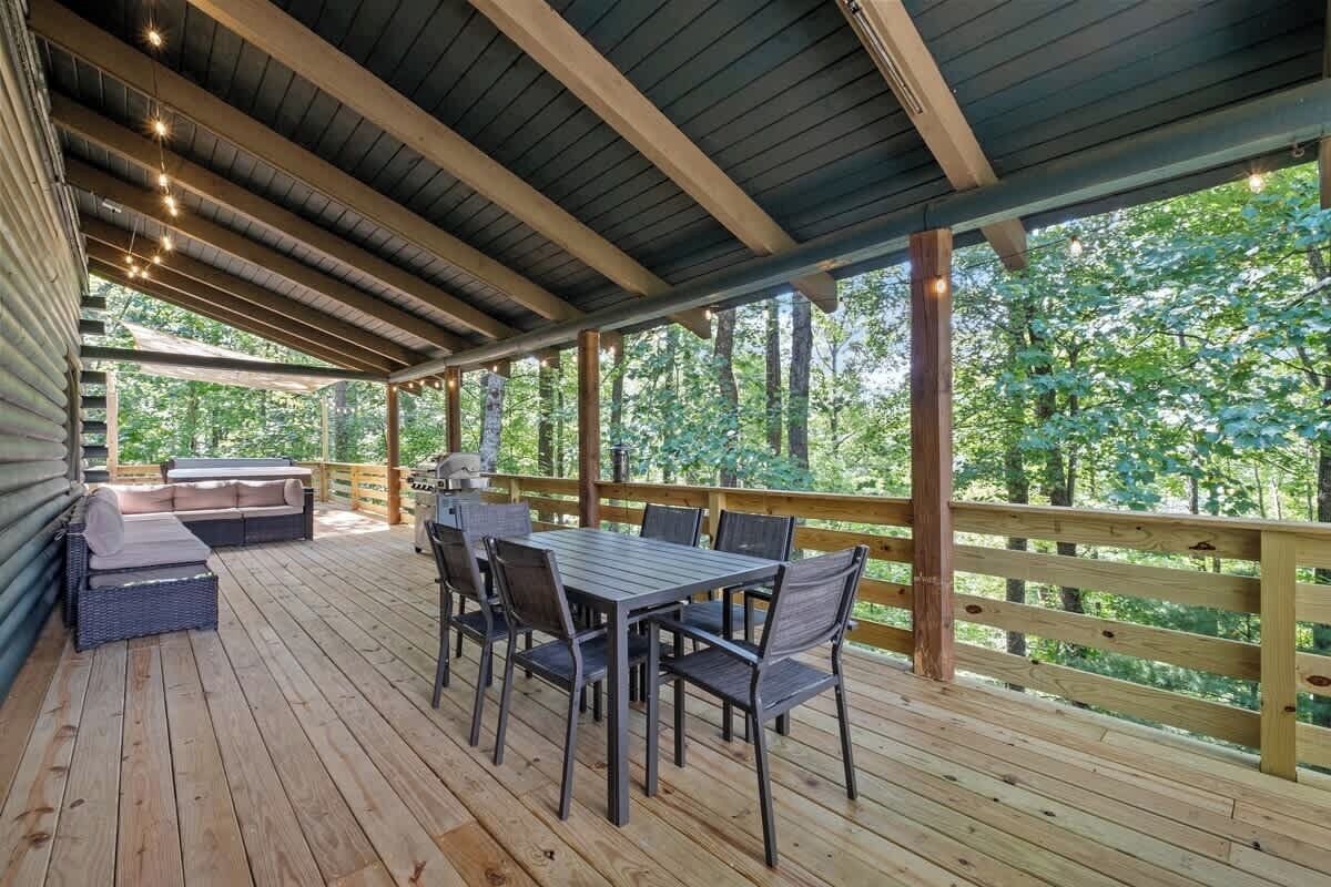 Una terraza techada con una mesa, sillas, un sofá y una parrilla.