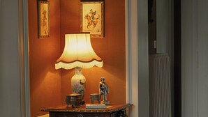 A hallway with a wooden console table, a lit table lamp, and framed artwork on the wall.