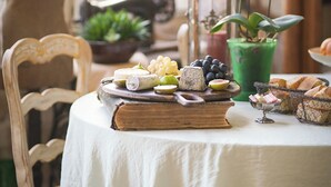 A table set with a variety of fruits and pastries, a green potted plant, and a decorative lantern.