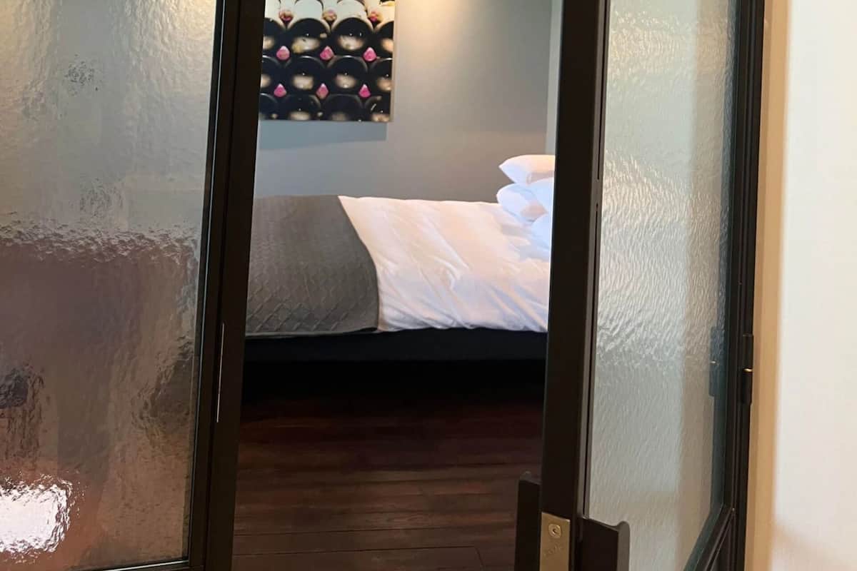 A hotel room with a bed, a wall-mounted artwork, and a wooden floor.