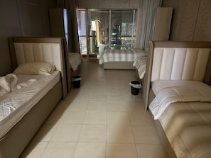 Une chambre d’hôtel avec deux lits, une porte vitrée donnant sur un balcon et une vue sur le paysage urbain.