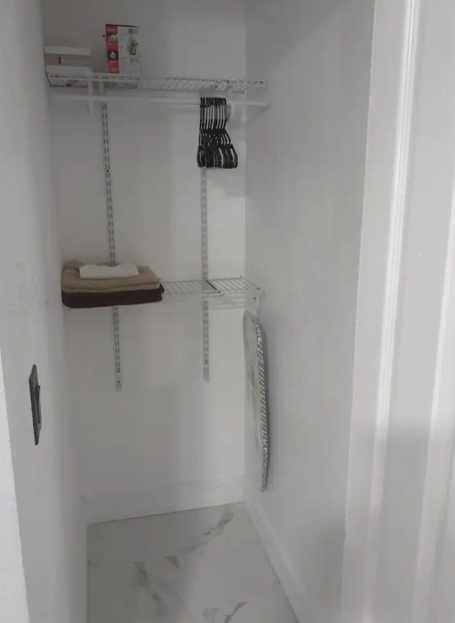A corner of a room with a white wall, a marble floor, and a white door.