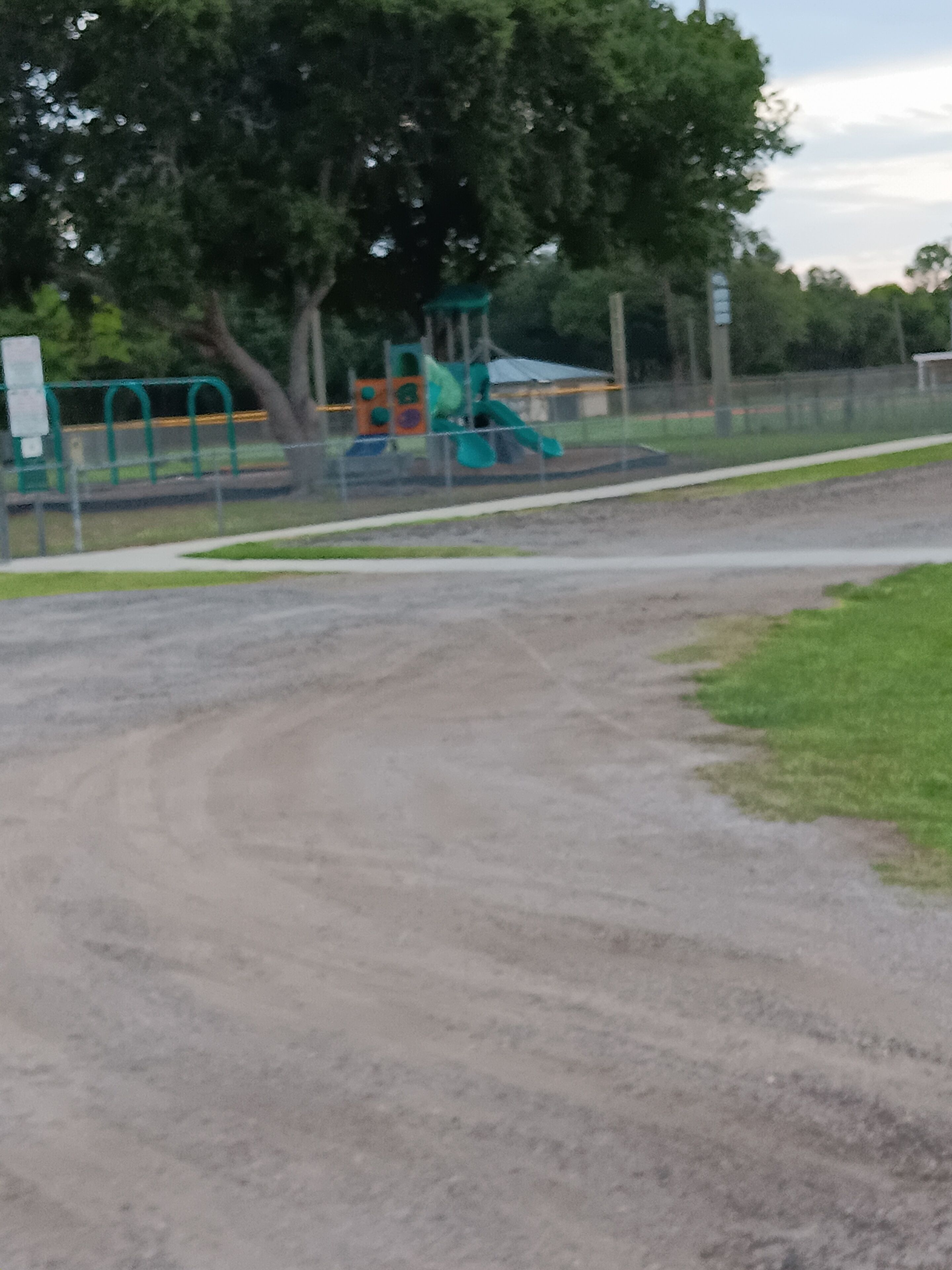 A gravel path leading to a playground with a slide and climbing structures.