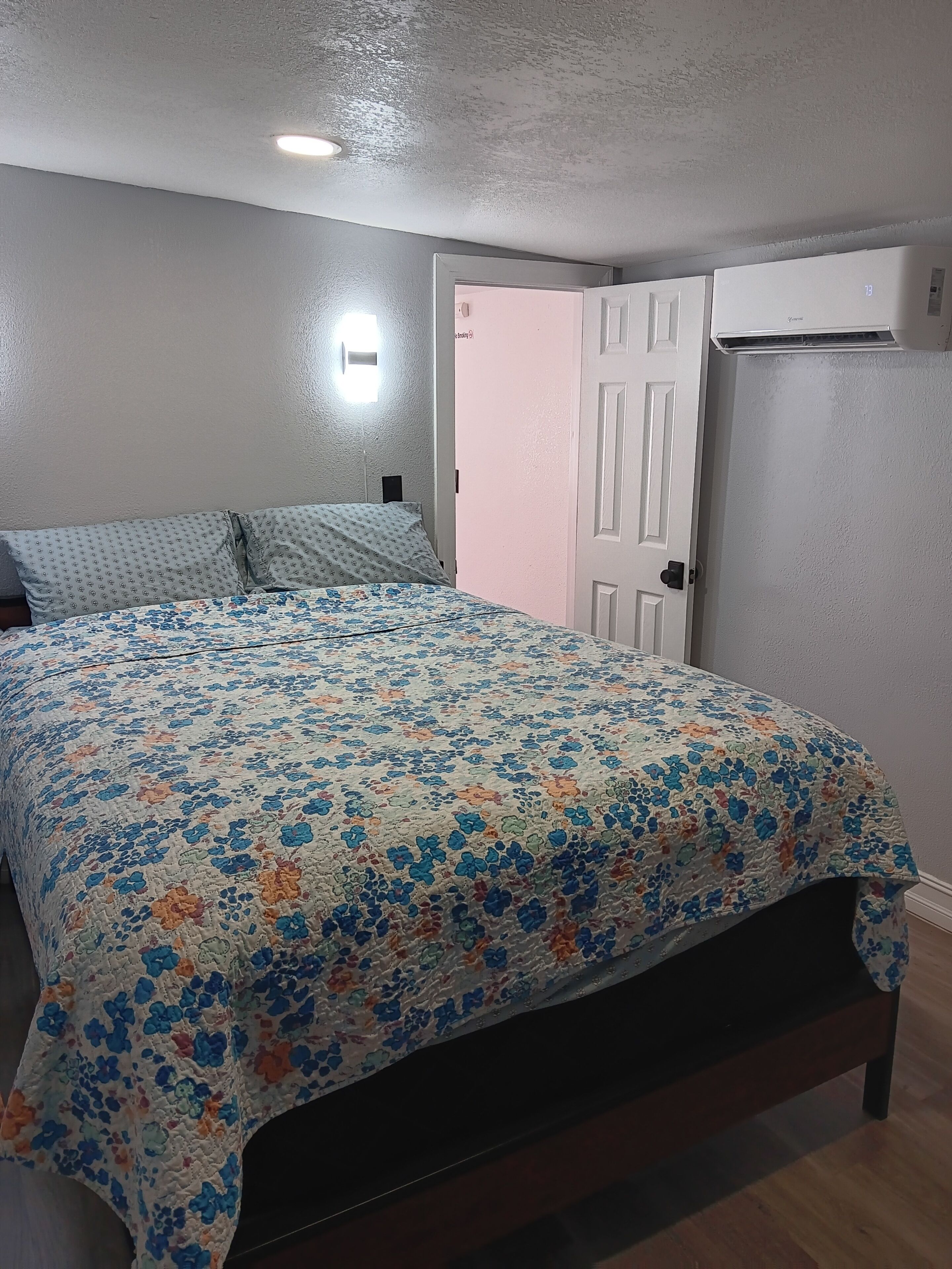 Een slaapkamer met een bed, een deur en een airconditioning.
