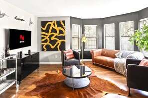A modern living room with a leather sofa, a round coffee table, and a TV displaying the Netflix logo.