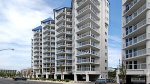 Un immeuble résidentiel moderne à plusieurs étages, doté de balcons, d’un toit plat et surplombant un ciel dégagé.