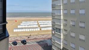 A view of a beach with beach huts and a parking area in front of a building with multiple windows. - Duplex at Albert Beach With Stunning Sea Views (Knokke-Heist)