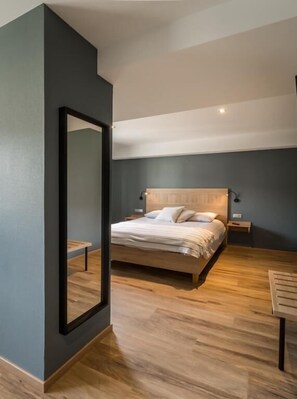 Una camera da letto moderna con un letto grande, una testiera in legno, comodini e uno specchio.
