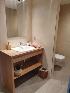 Un bagno moderno con un mobile bagno in legno, uno specchio grande e un water.