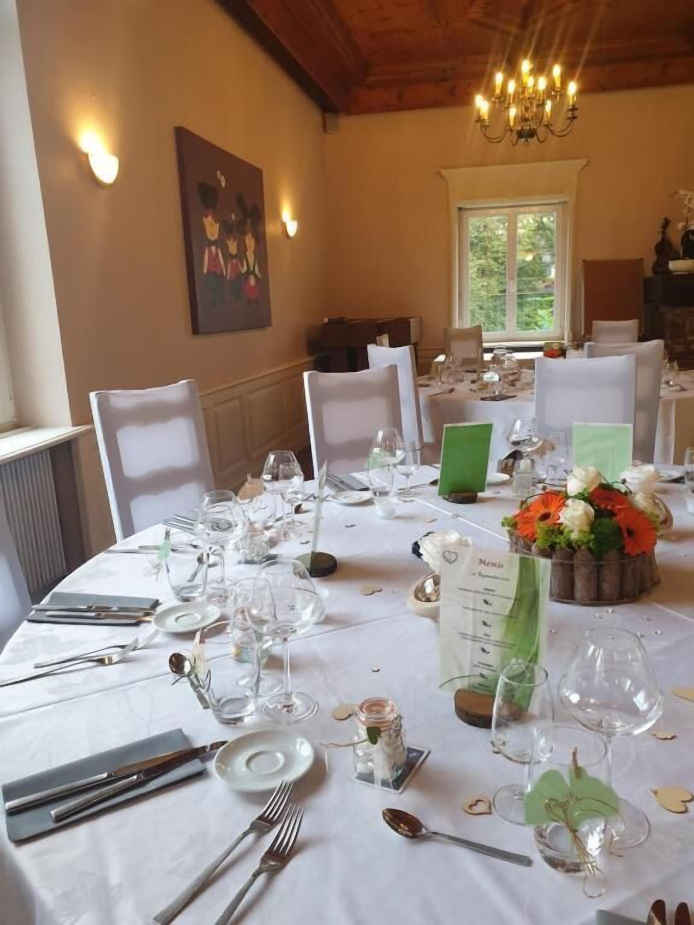 Un comedor con manteles blancos, sillas y un candelabro.
