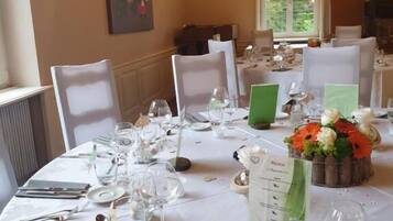 Un comedor con manteles blancos, sillas y un candelabro.