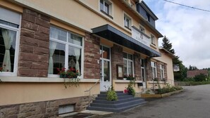 A two-story building with a stone facade, a flat roof, and a sign indicating it is a restaurant. - Au Wingenerhof (Wingen-sur-Moder)