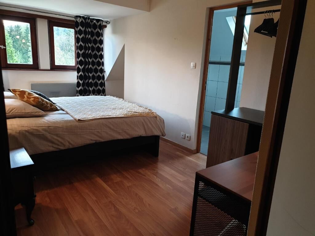 A bedroom with a bed, a nightstand, a dresser, and a window with curtains.