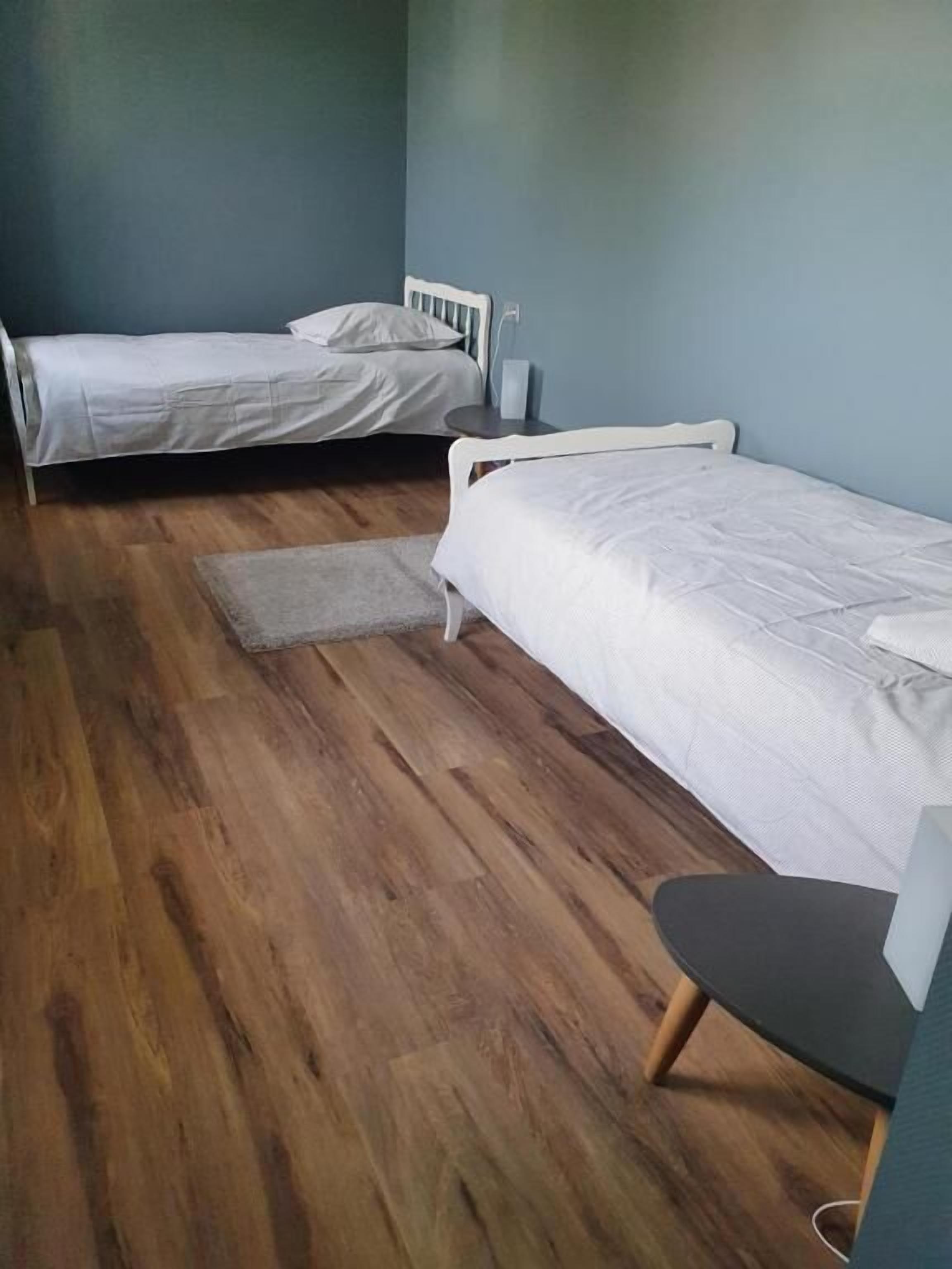 A room with two single beds, a small table, and a chair.