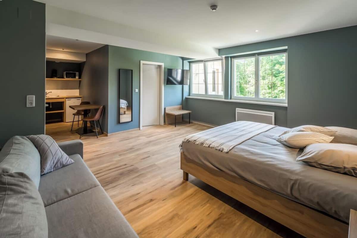 Un dormitorio moderno con una cama grande, un sofá, un escritorio y un televisor.