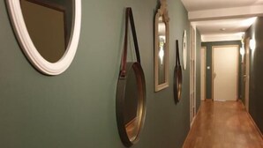 A hallway with green walls, wooden flooring, and several mirrors and picture frames. - Au Wingenerhof (Wingen-sur-Moder)