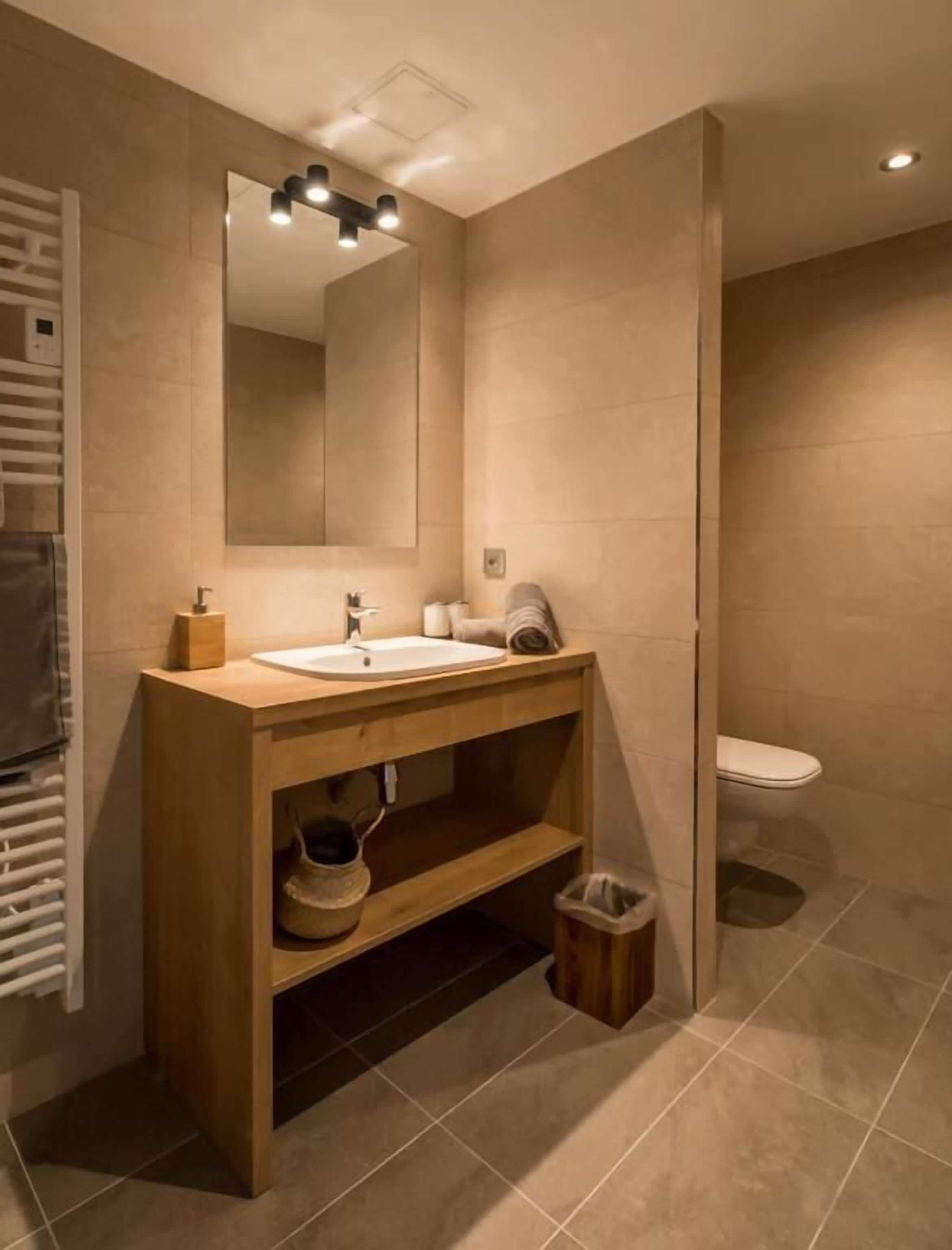Ein modernes Badezimmer mit einem Holzlager, einem großen Spiegel und einer Toilette.