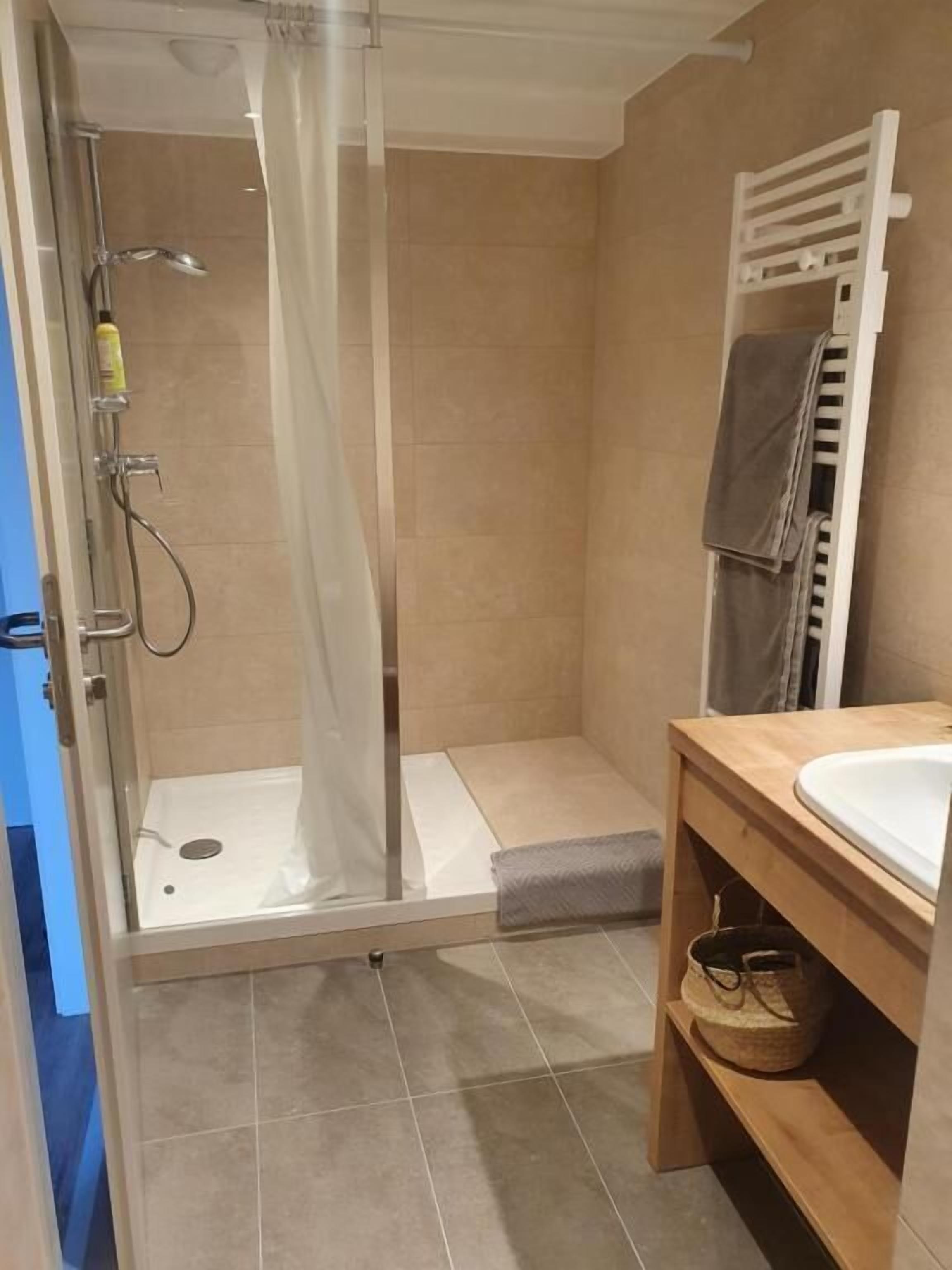 Ein Badezimmer mit einer gläsernen Duschkabine, einem hölzernen Waschtisch und einem Handtuchhalter.