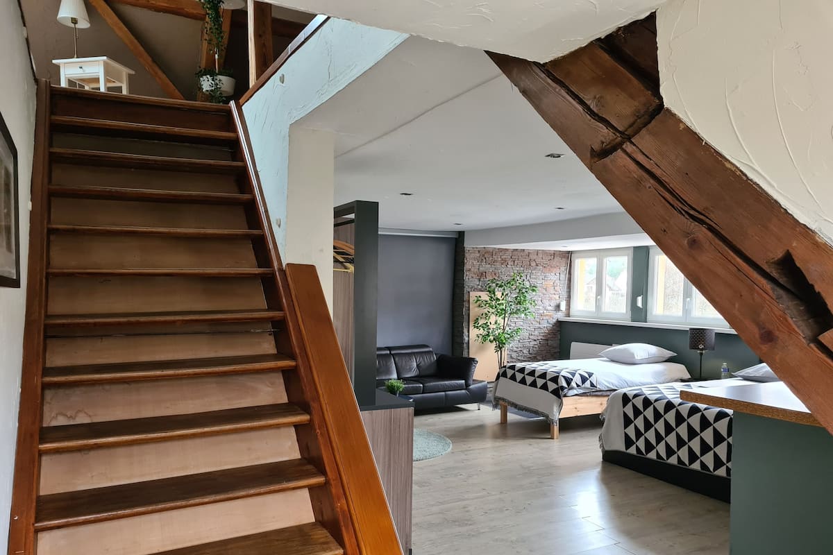 Una escalera que lleva a una sala de estar con una cama, un sofá y un televisor.
