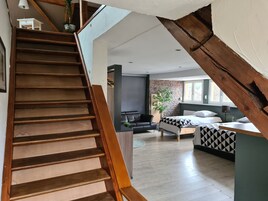 Una escalera que lleva a una sala de estar con una cama, un sofá y un televisor.