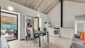 Eine moderne Küche mit Essbereich, einer Waschmaschine und Blick ins Freie.