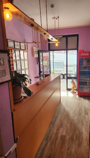Un comptoir d’accueil avec un plan de travail en bois, des certificats encadrés, un réfrigérateur Coca-Cola et une sculpture d’oiseau.