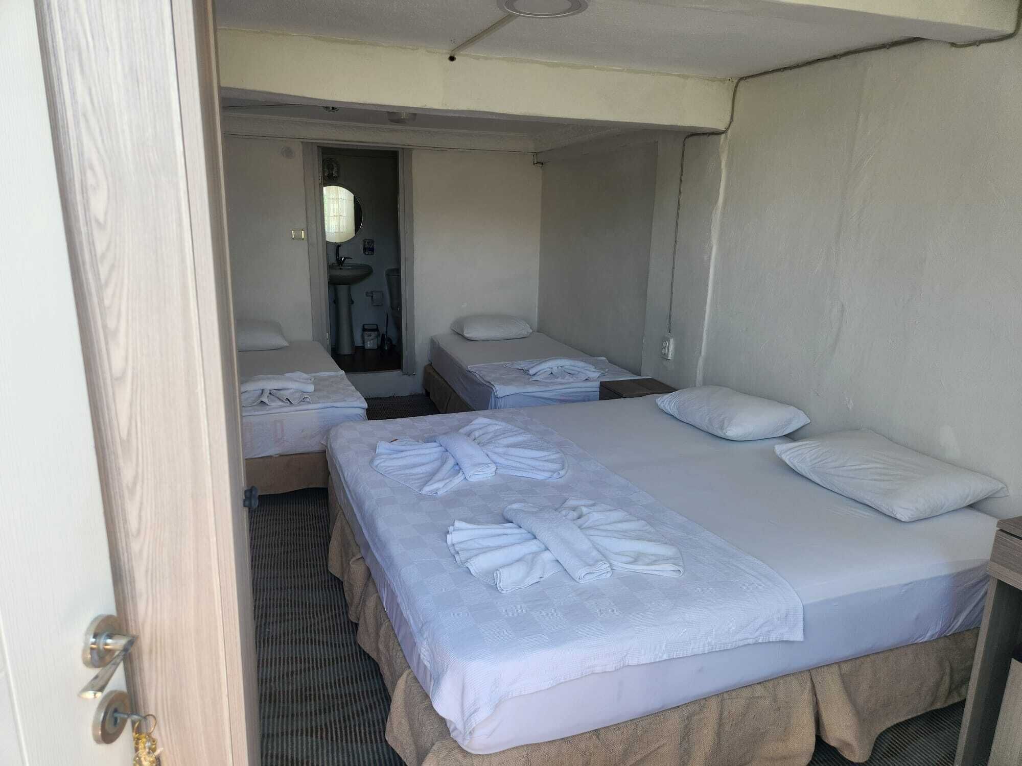 A hotel room with two beds, each with a pillow and a folded towel.