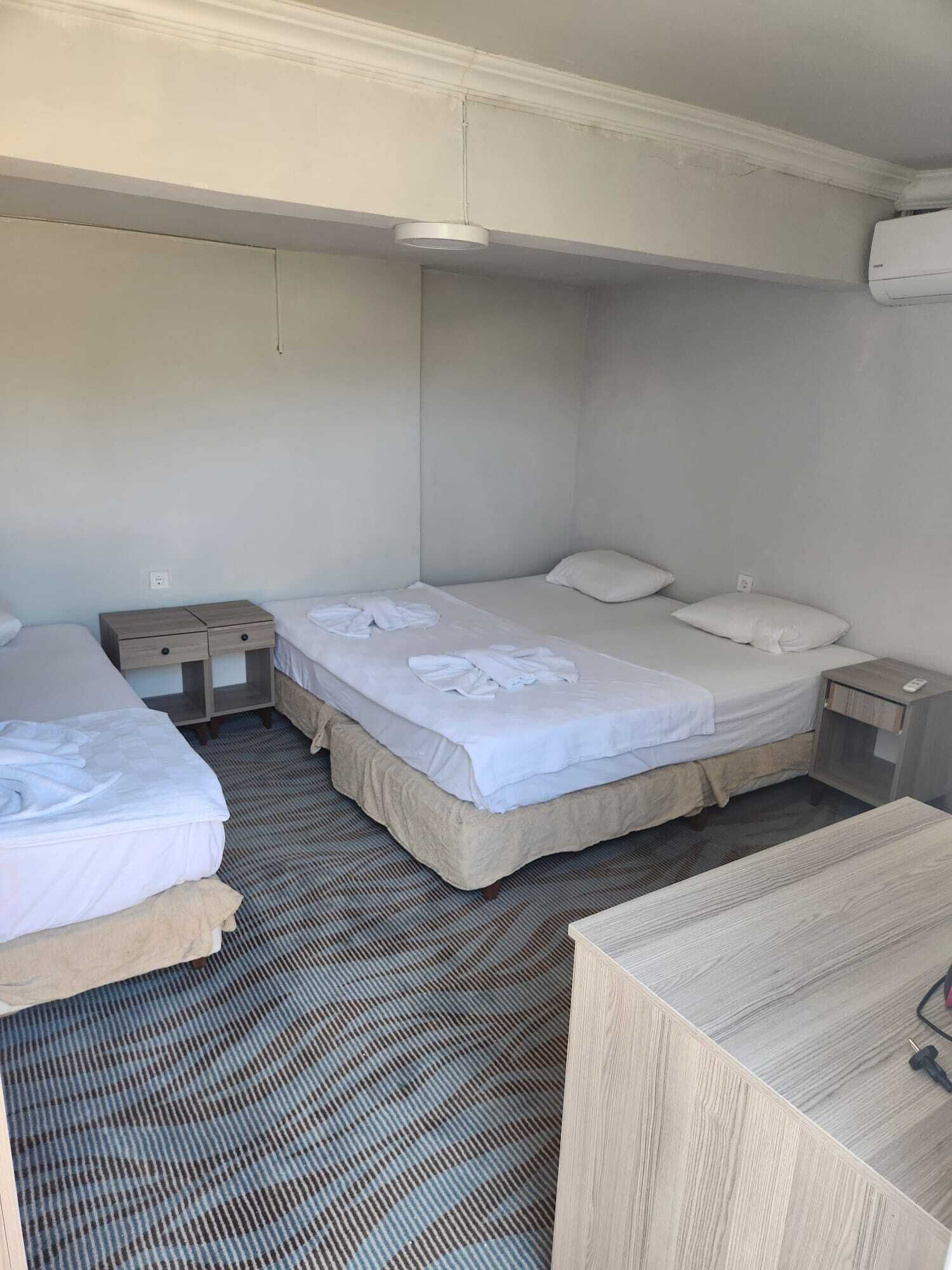 Quarto de hotel com duas camas, uma pequena mesa e uma cadeira.