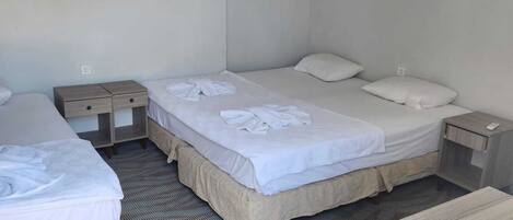 Quarto de hotel com duas camas, uma pequena mesa e uma cadeira.