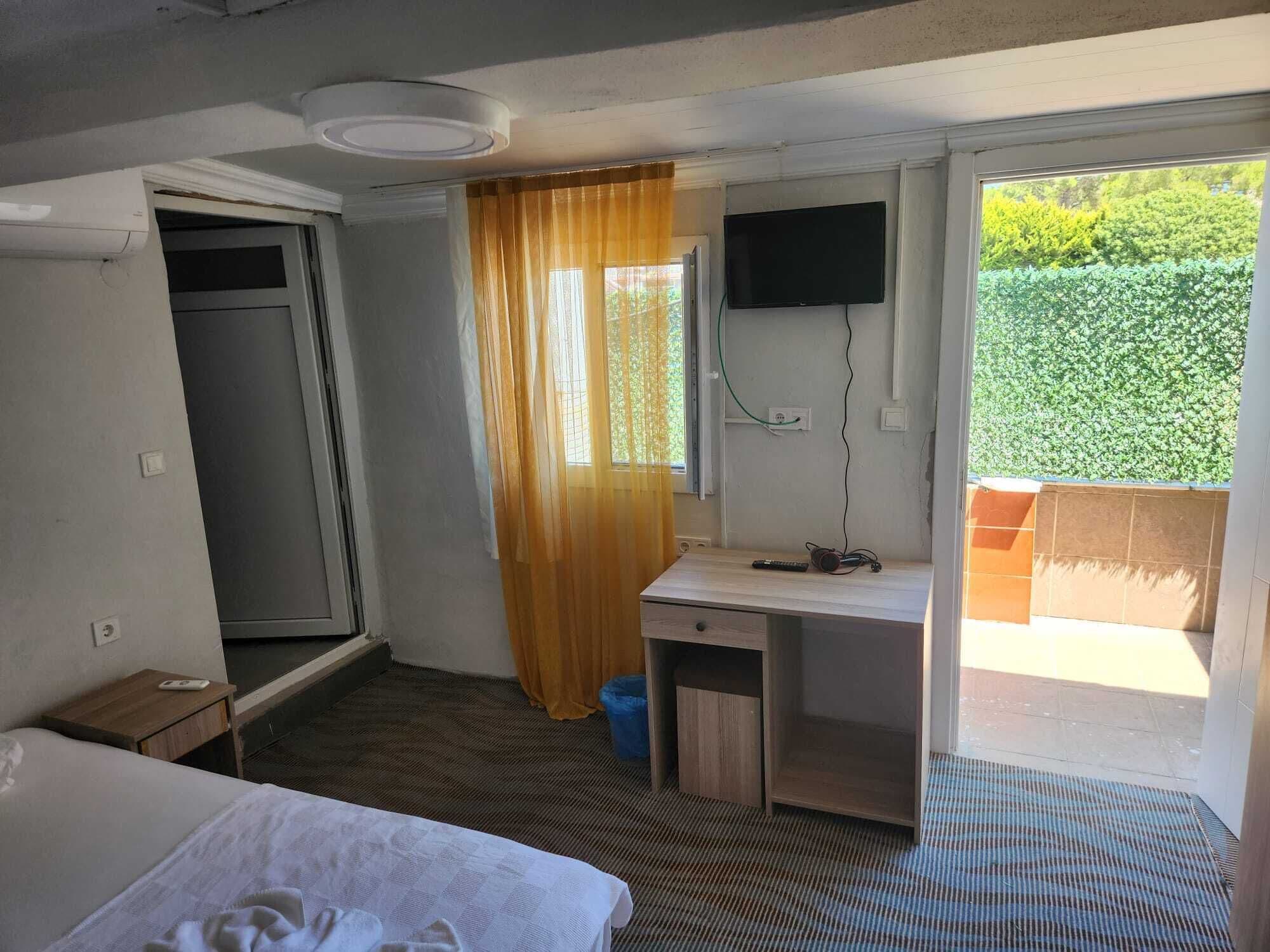 A hotel room with a bed, a desk, a television, and a window with curtains.