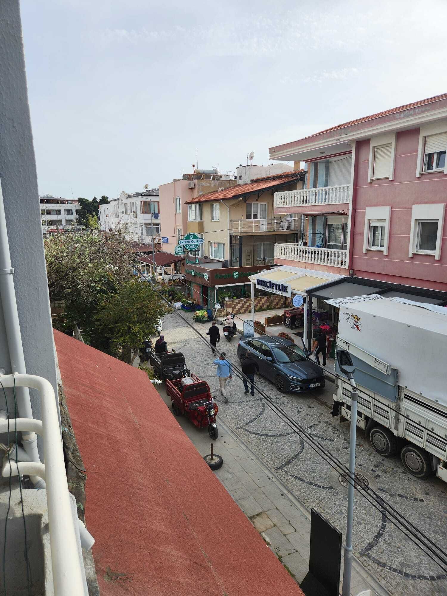 Vista callejera con edificios, un camión estacionado y un vehículo rojo.