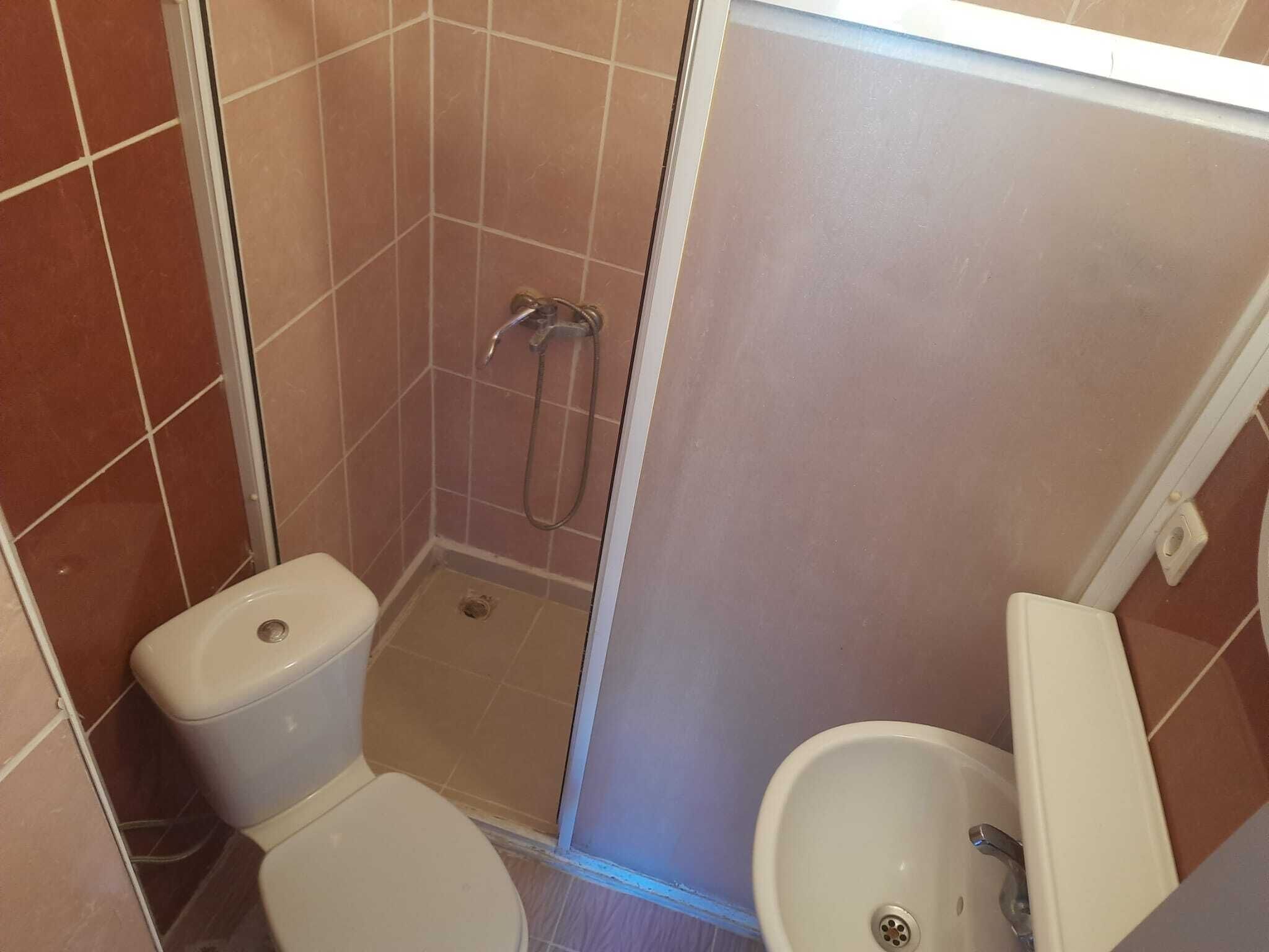 Et lille badeværelse med toilet, brusekabine og håndvask.