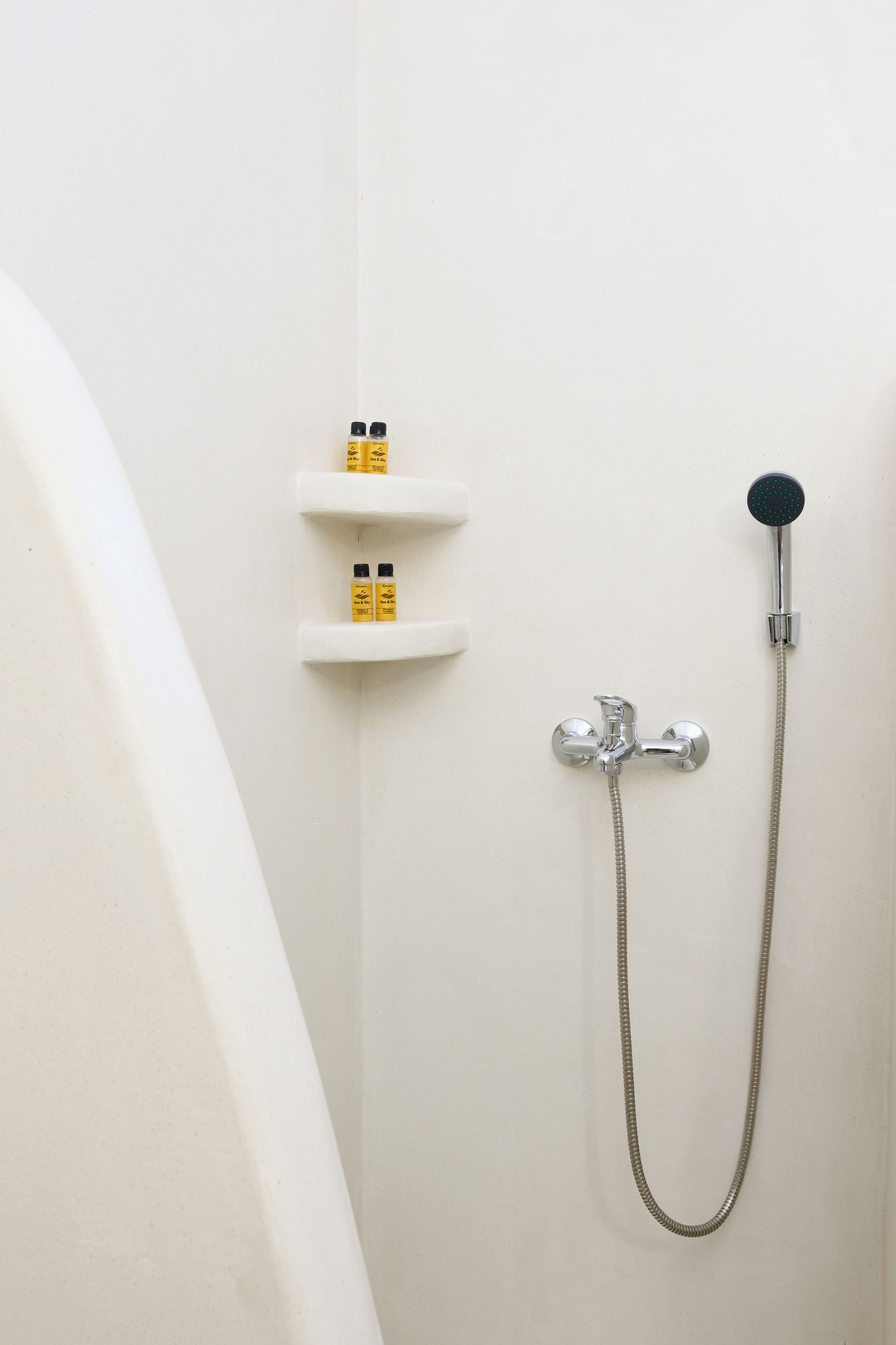 Une salle de bain avec une douche, un robinet et deux distributeurs de savon sur un mur blanc.