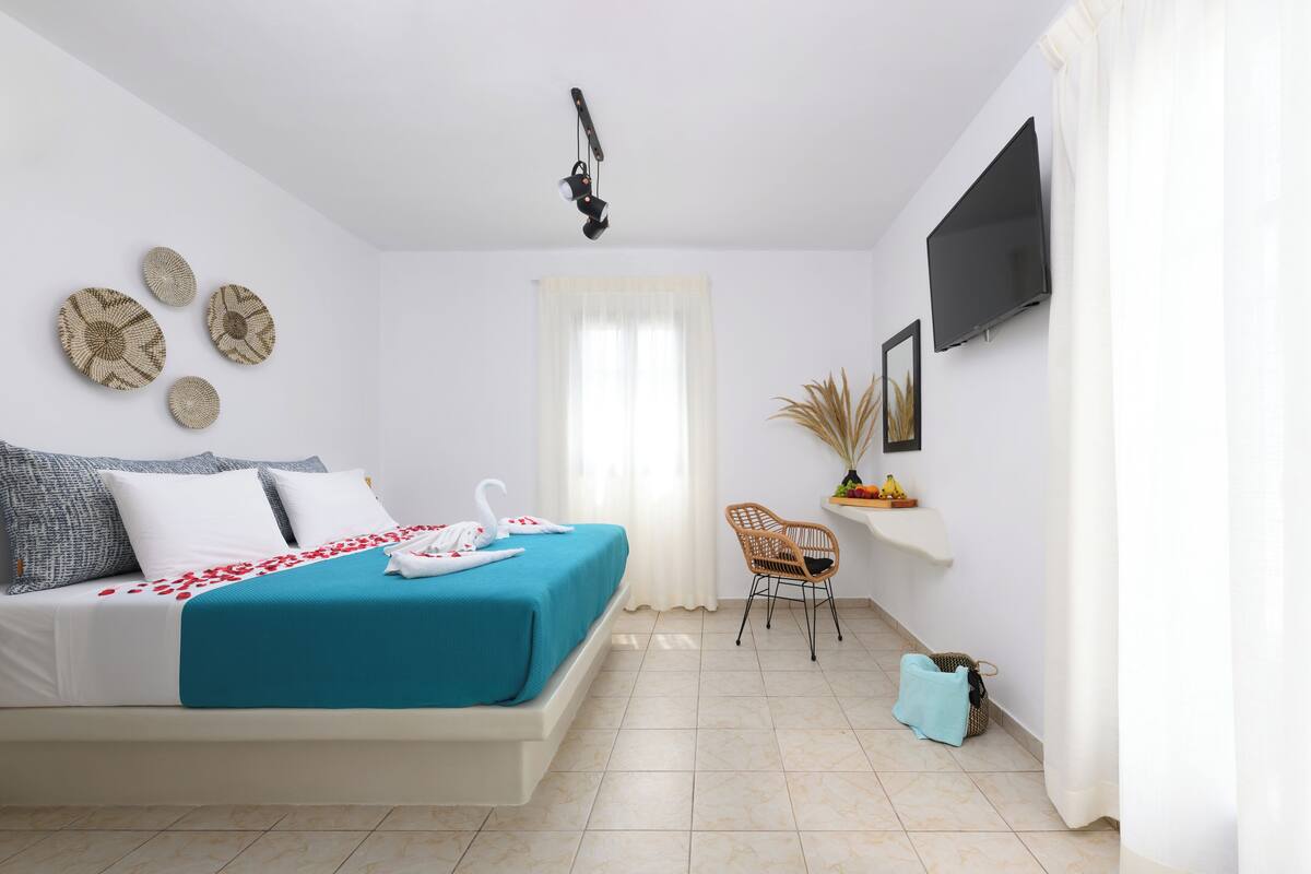 Quarto com cama, cadeira, televisão e decorações nas paredes.