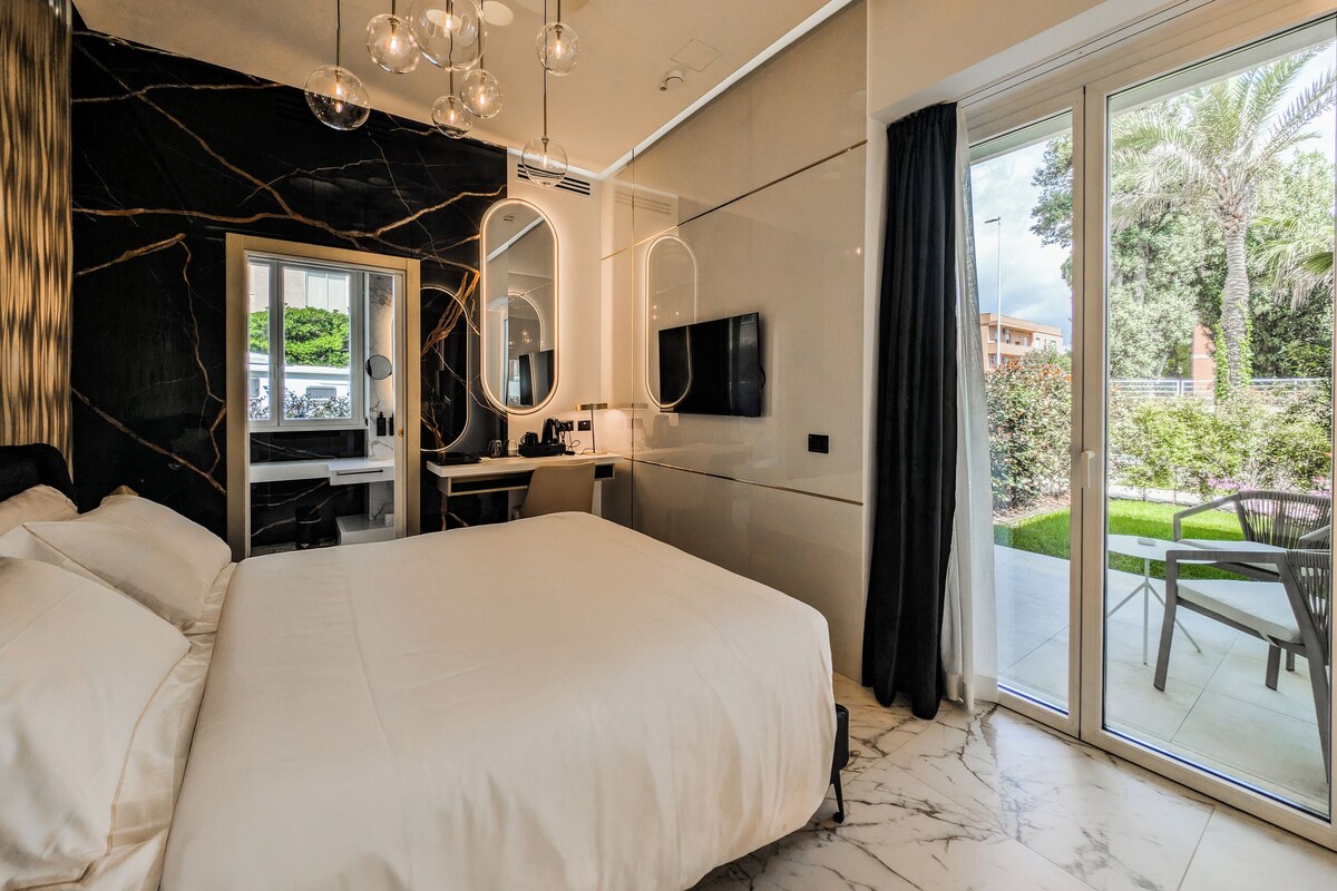 Un dormitorio moderno con una cama grande, un escritorio y un baño con espejo.