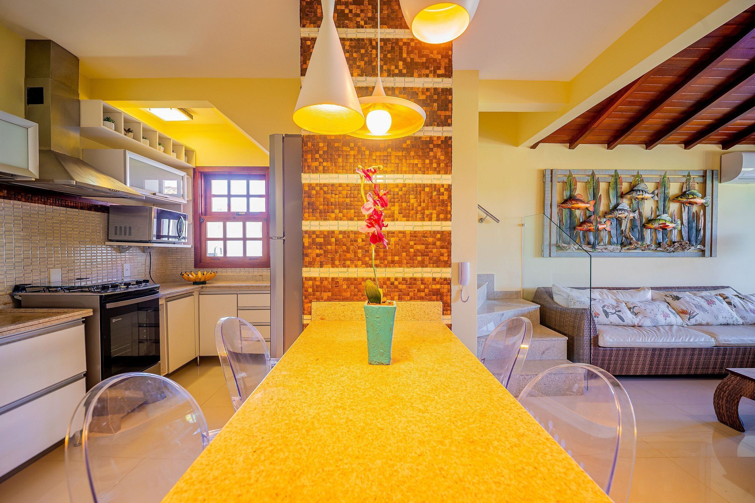 A modern kitchen with a yellow countertop, a dining table, and a seating area with a sofa and chairs.