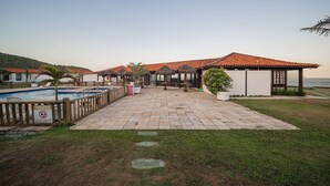 A pool area with a tiled deck, a sign prohibiting entry, and a view of the sea. - Bz60 Casa em condomínio pé na areia (Buzios)