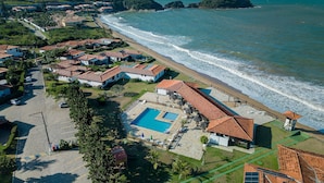 An aerial view of a coastal resort with villas, a swimming pool, and a beach. - Bz60 Casa em condomínio pé na areia (Buzios)