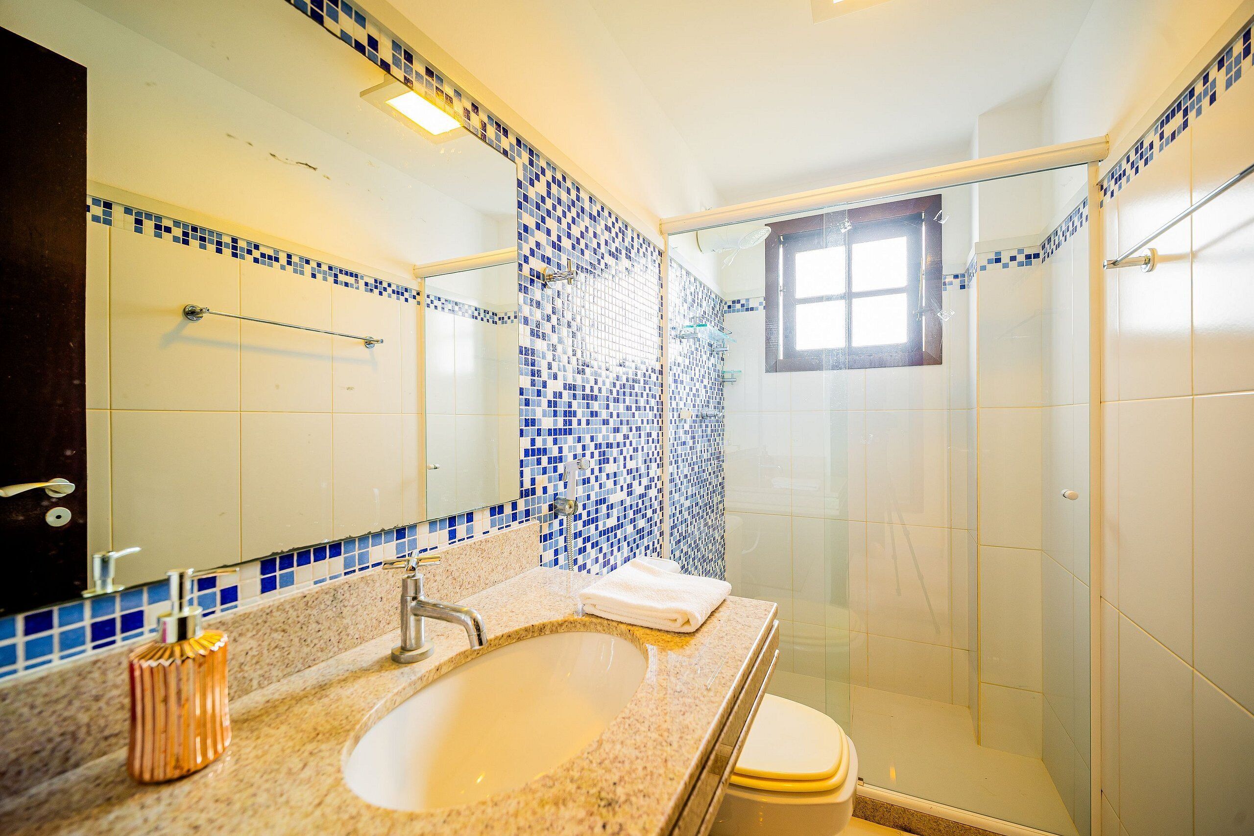 A bathroom with a sink, mirror, and shower.