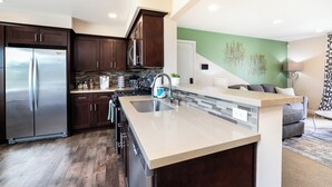A modern kitchen with dark wood cabinets, stainless steel appliances, and a light-colored island with a sink. - Peaceful & Gated 2 King Bd 2 Bth, 1 Gig WiFi near CLU, FSAC & Proactive Sports (Thousand Oaks)