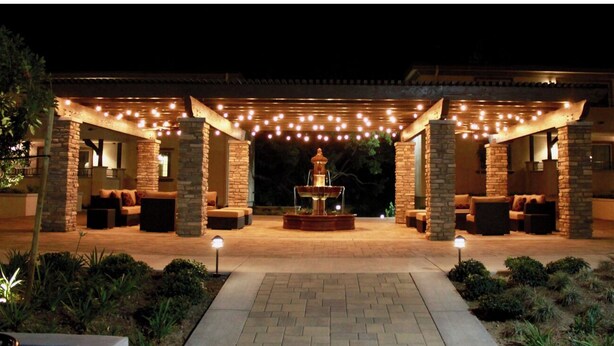 An outdoor patio area with stone pillars, a central fountain, and string lights. - Peaceful & Gated 2 King Bd 2 Bth, 1 Gig WiFi near CLU, FSAC & Proactive Sports (Thousand Oaks)