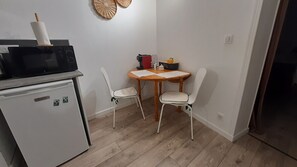 Cocina compacta con refrigerador, microondas y una pequeña mesa con sillas.