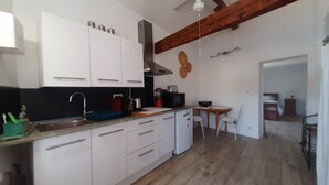 A compact kitchen with white cabinets, a wooden ceiling, and a small dining area with a table and chairs. - Beautiful view (Agde)